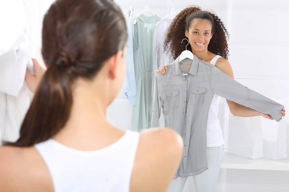 A woman looking at a shirt in a closet.