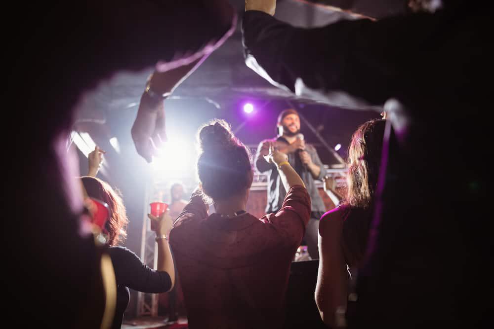 A group of people at a concert raising their hands in the air, enjoying the vibrant ambiance and collective energy.