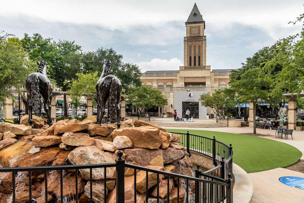 A statue of a horse in front of a fountain.