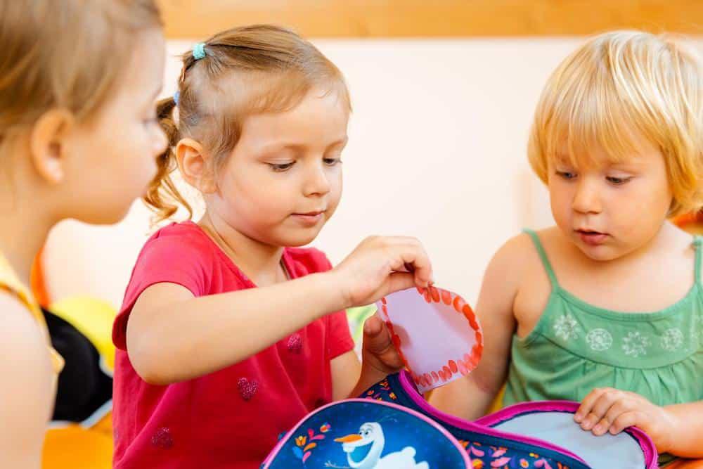 Two children engaged in sharing and exploring the contents of a backpack.