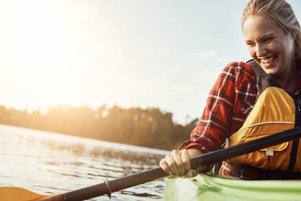 A woman is paddling a kayak on a lake.