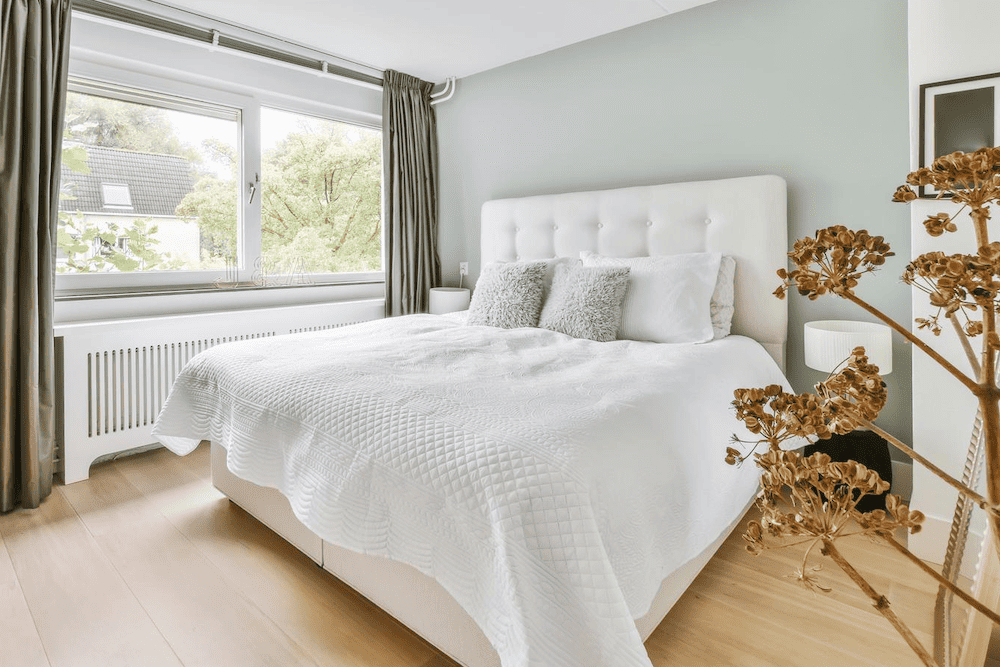 A bedroom with a white bed and green walls perfect for a bachelorette party in Fredericksburg.