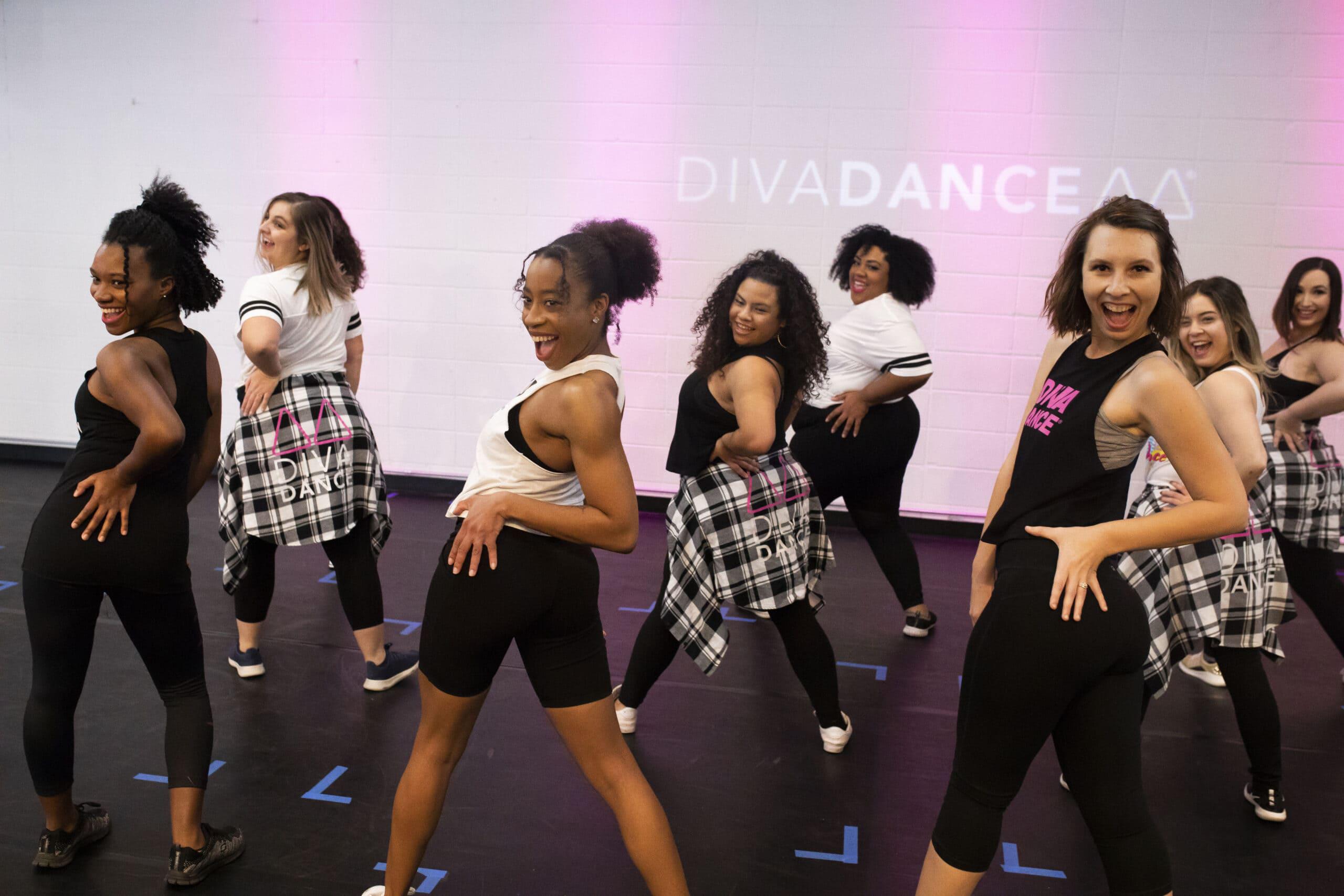 Class at DivaDance HQ in Austin: adults laughing and dancing together under pink and purple lights.