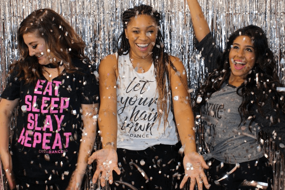 Three girls dancing and throwing confetti during a DivaDance class