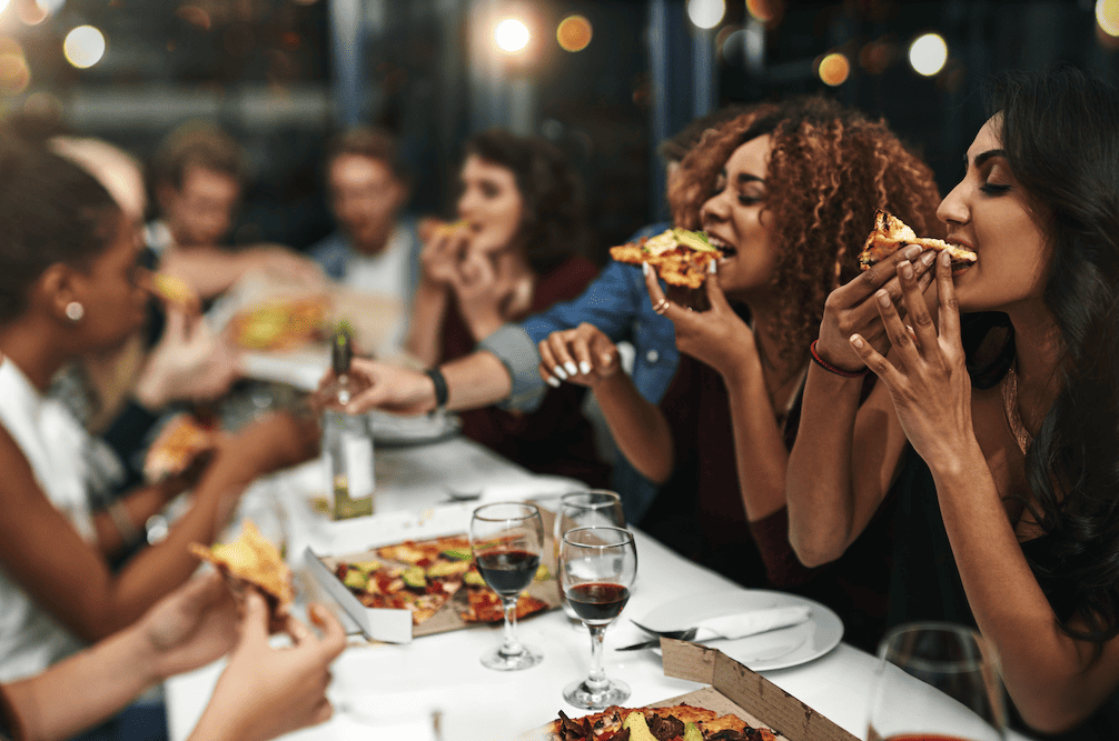 A group of people eating pizza at a restaurant.