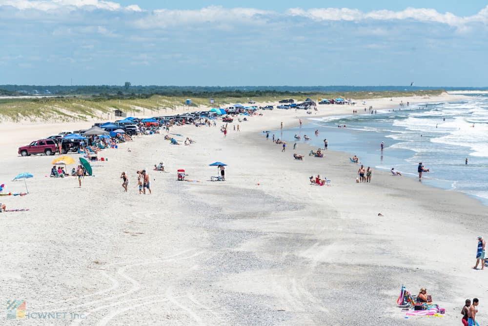 The beach is crowded with people and umbrellas.