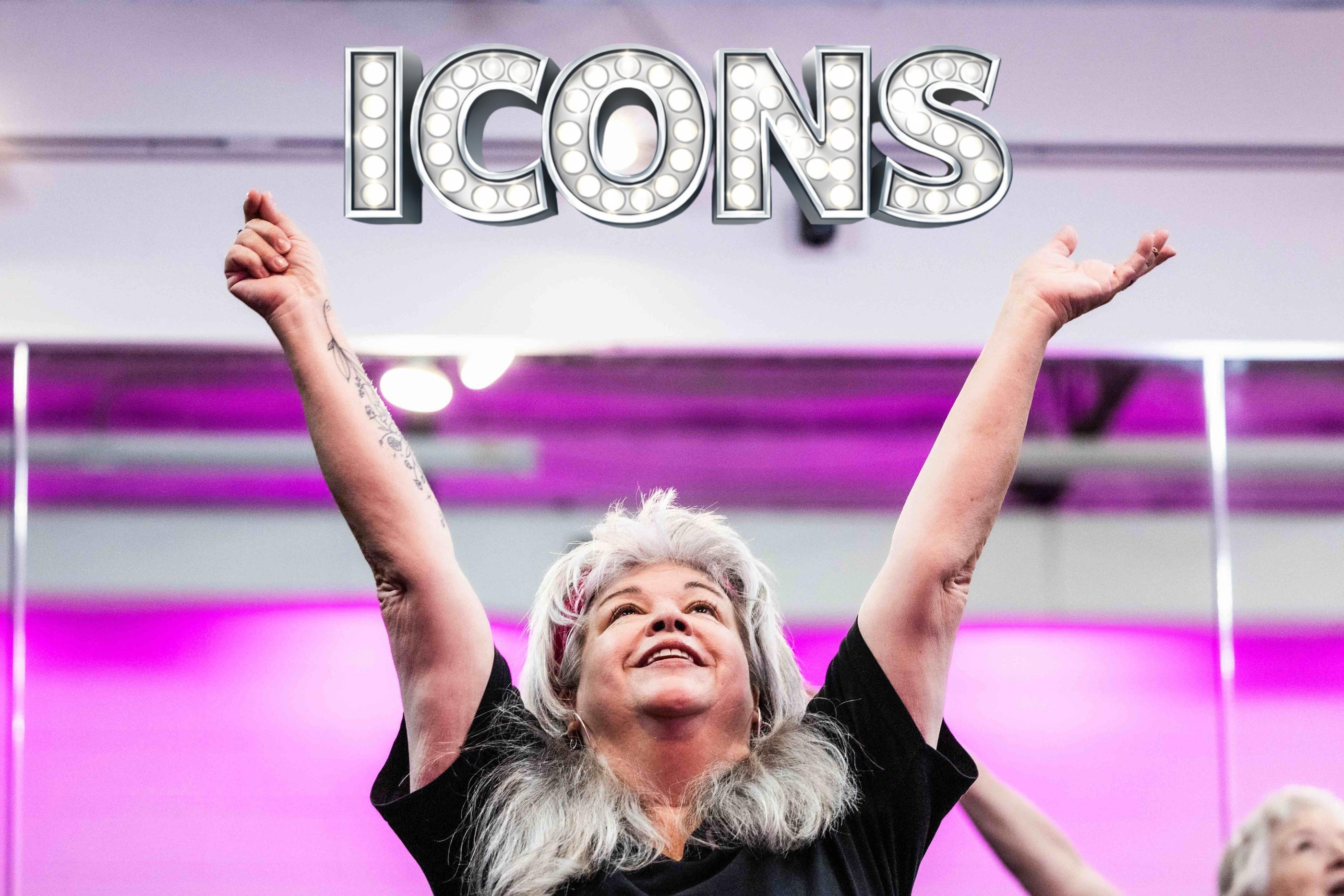 Woman with silver hair smiling and reaching both arms overhead in a DivaDance ICONS low-impact dance class, magenta studio lighting behind her, other adult students mid-movement at right.