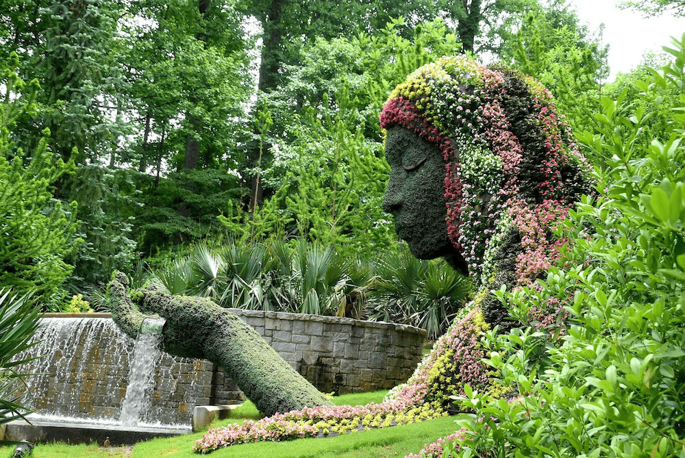 Sculpted garden figure with floral decoration emitting water into a pond, perfect for a Sandy Springs bachelorette.