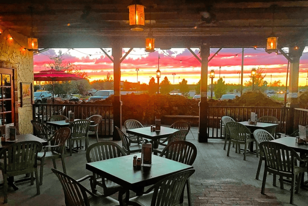 An outdoor patio with tables and chairs at sunset.