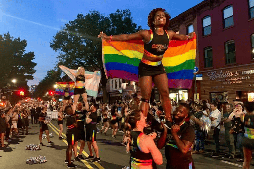 A group of people holding up a rainbow flag during a parade in Brooklyn.