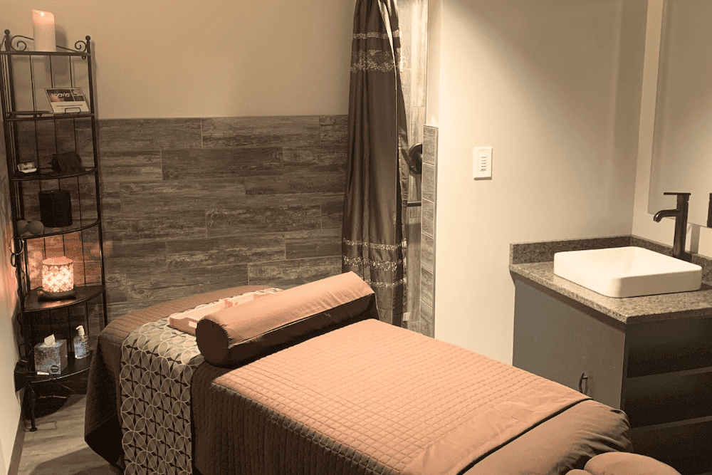 A room with a massage table and a sink.