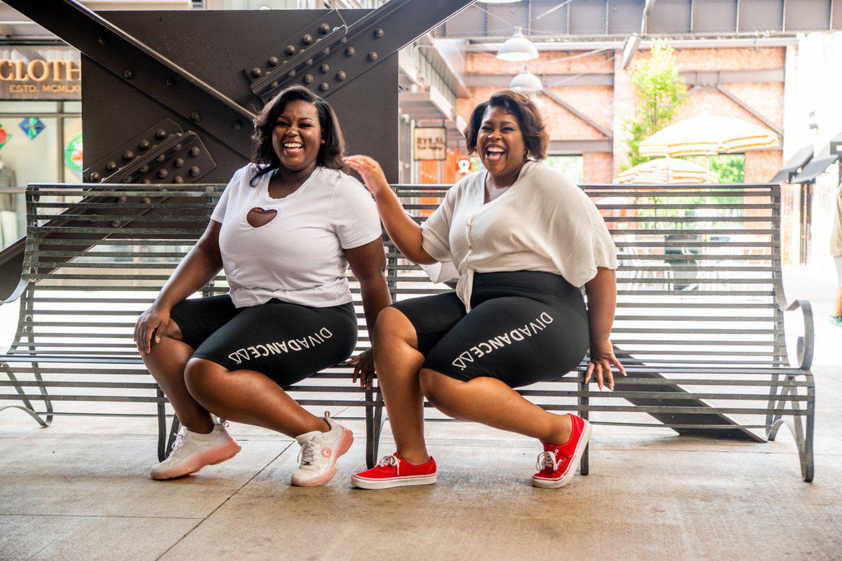 Two adult friends laughing together on a bench in DivaDance leggings