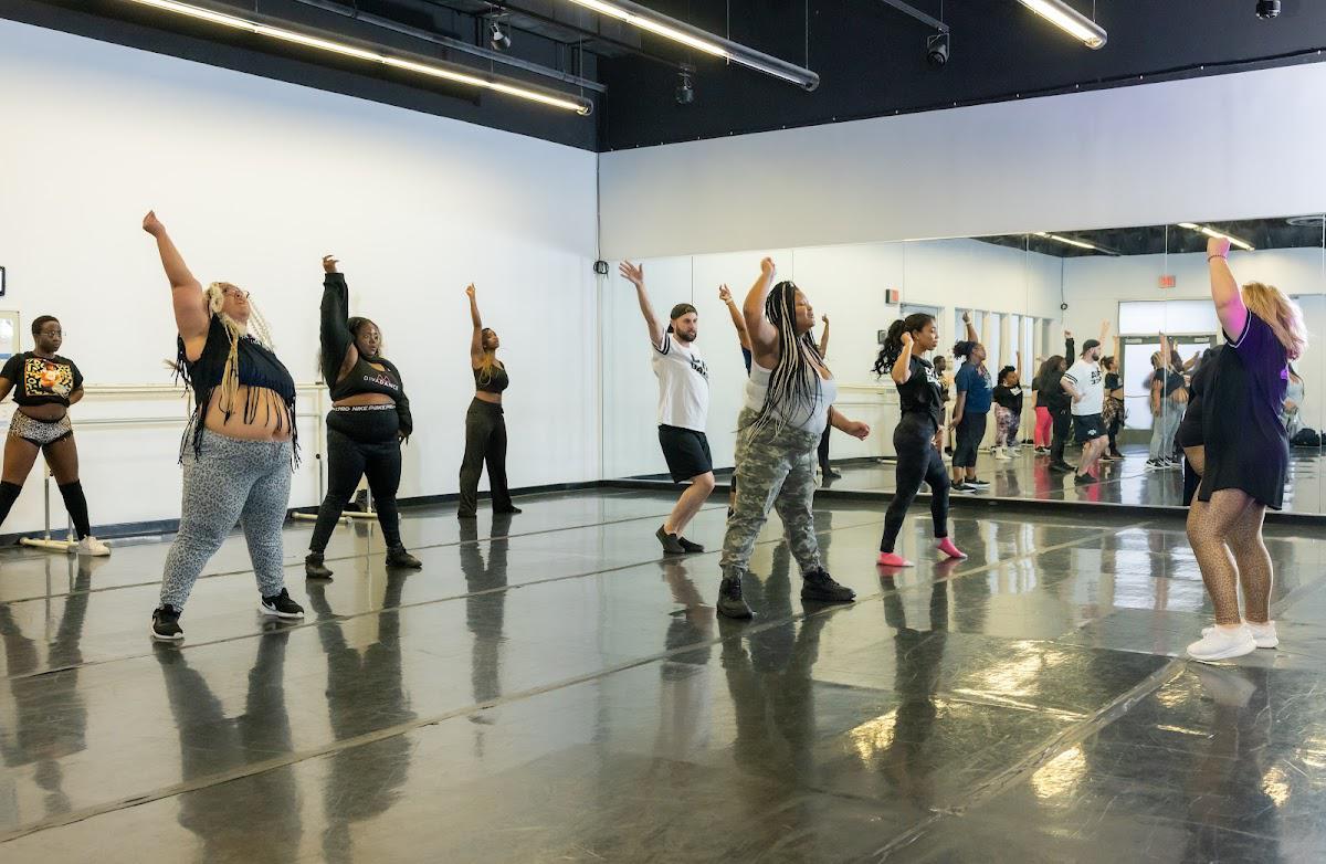 DivaDance members of different ages and sizes dancing with arms raised during a class