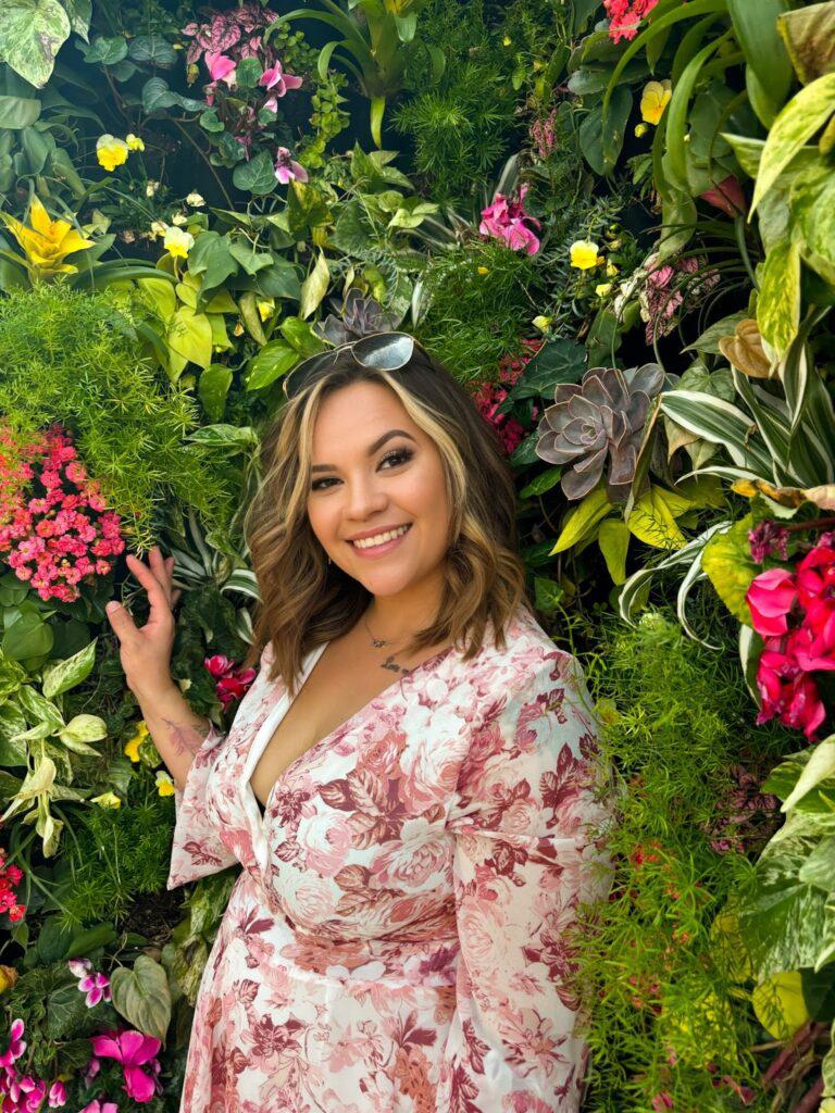 Woman standing and smiling in the middle of beautiful trees withs flowers